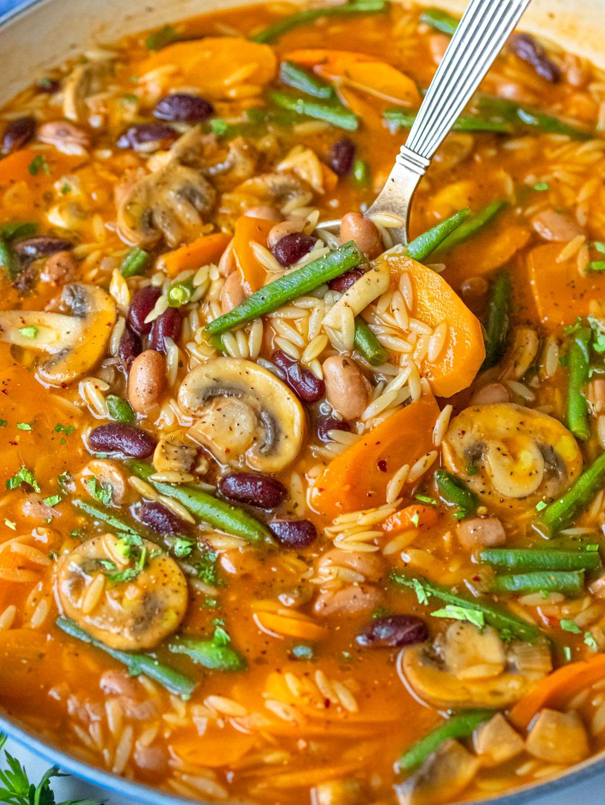 Finished soup close up creamy three bean orzo soup showing tender orzo and vegetables.