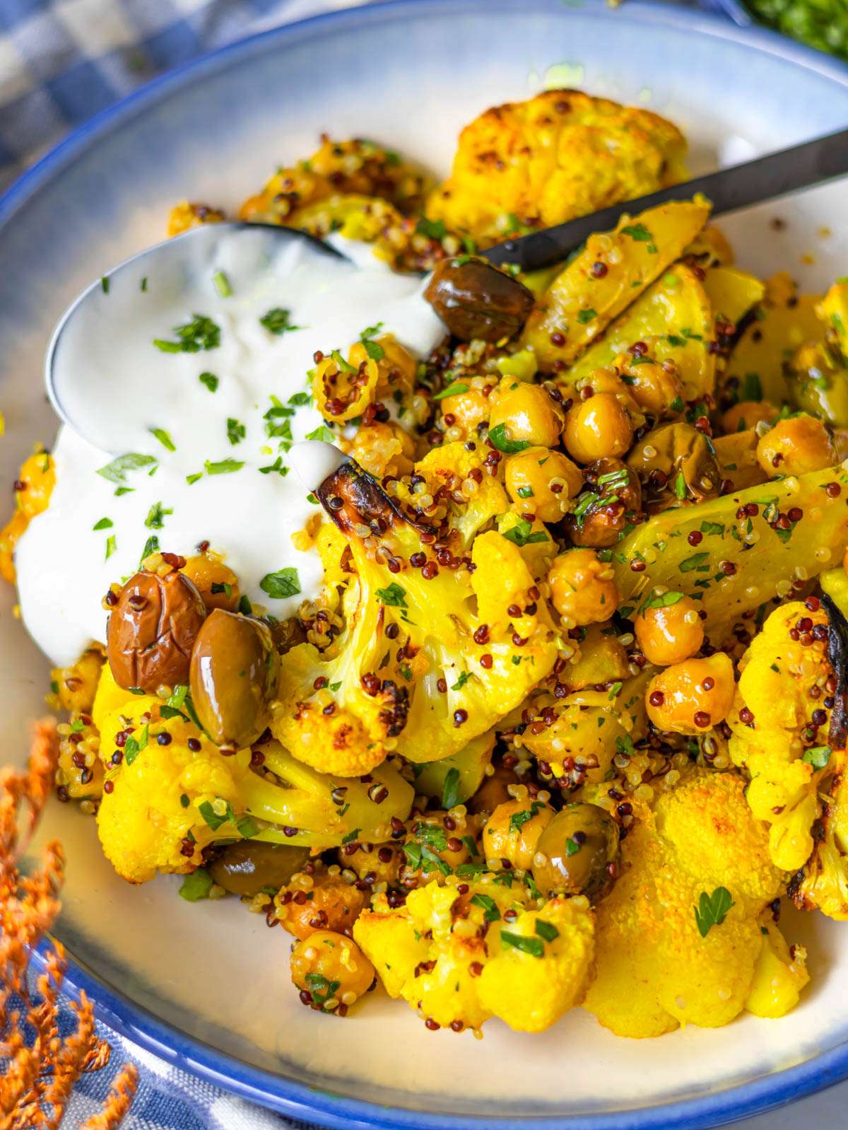 Finished turmeric cauliflower and chickpeas with quinoa and yogurt in a bowl.