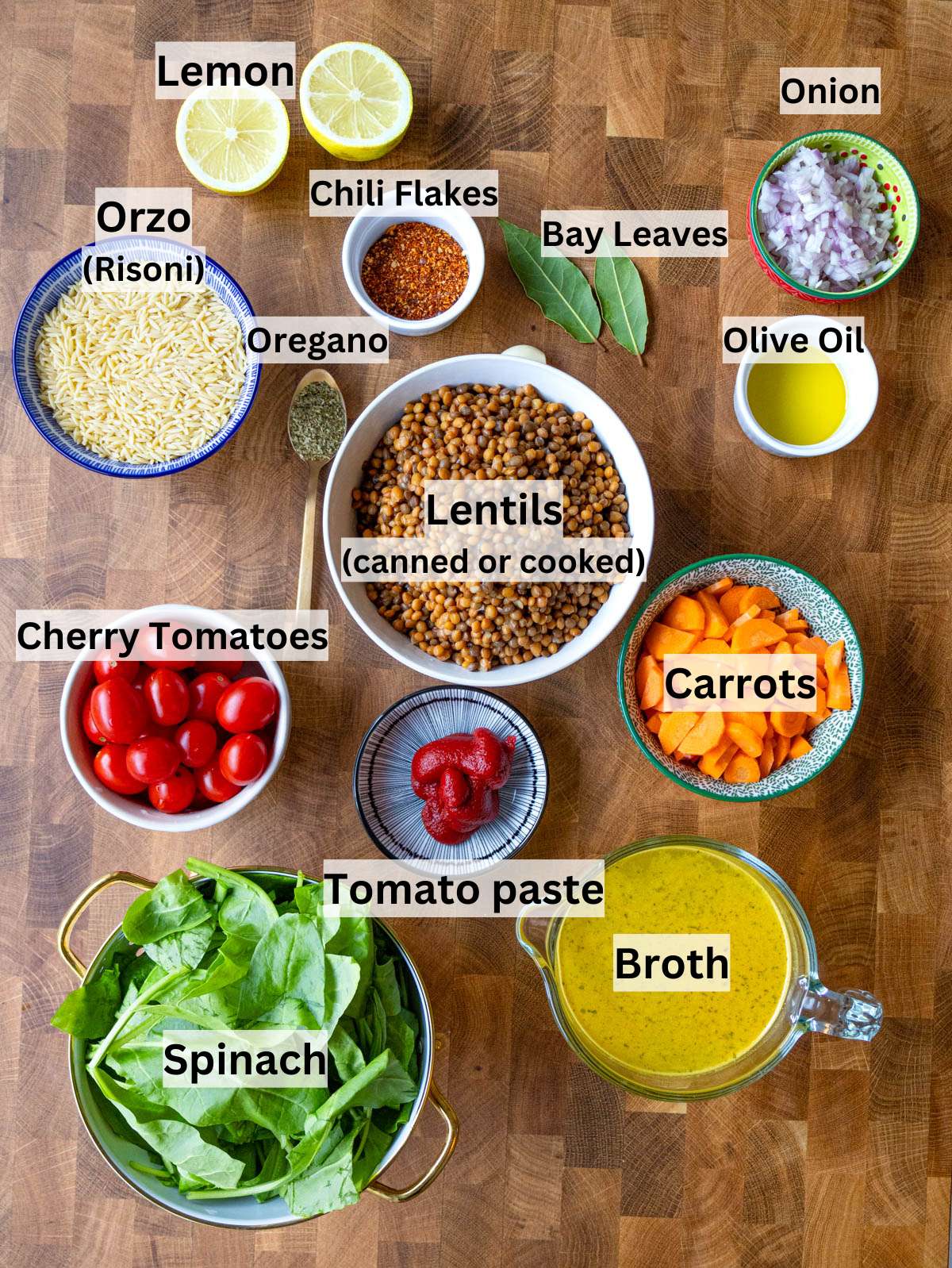 Fresh ingredients for lentil and orzo including onion carrots garlic orzo and spinach on a table.
