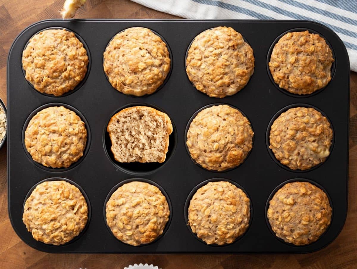 Freshly baked banana oatmeal muffins in a muffin pan showing golden tops and soft, fluffy texture.