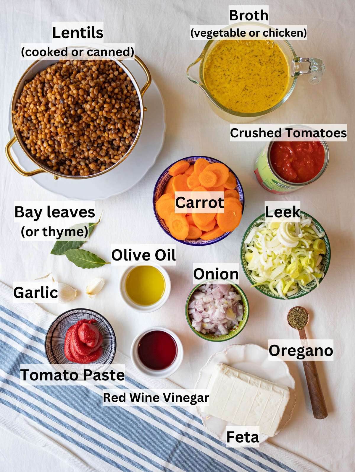 Ingredients for Greek lentil soup arranged on a table with olive oil and vegetables.