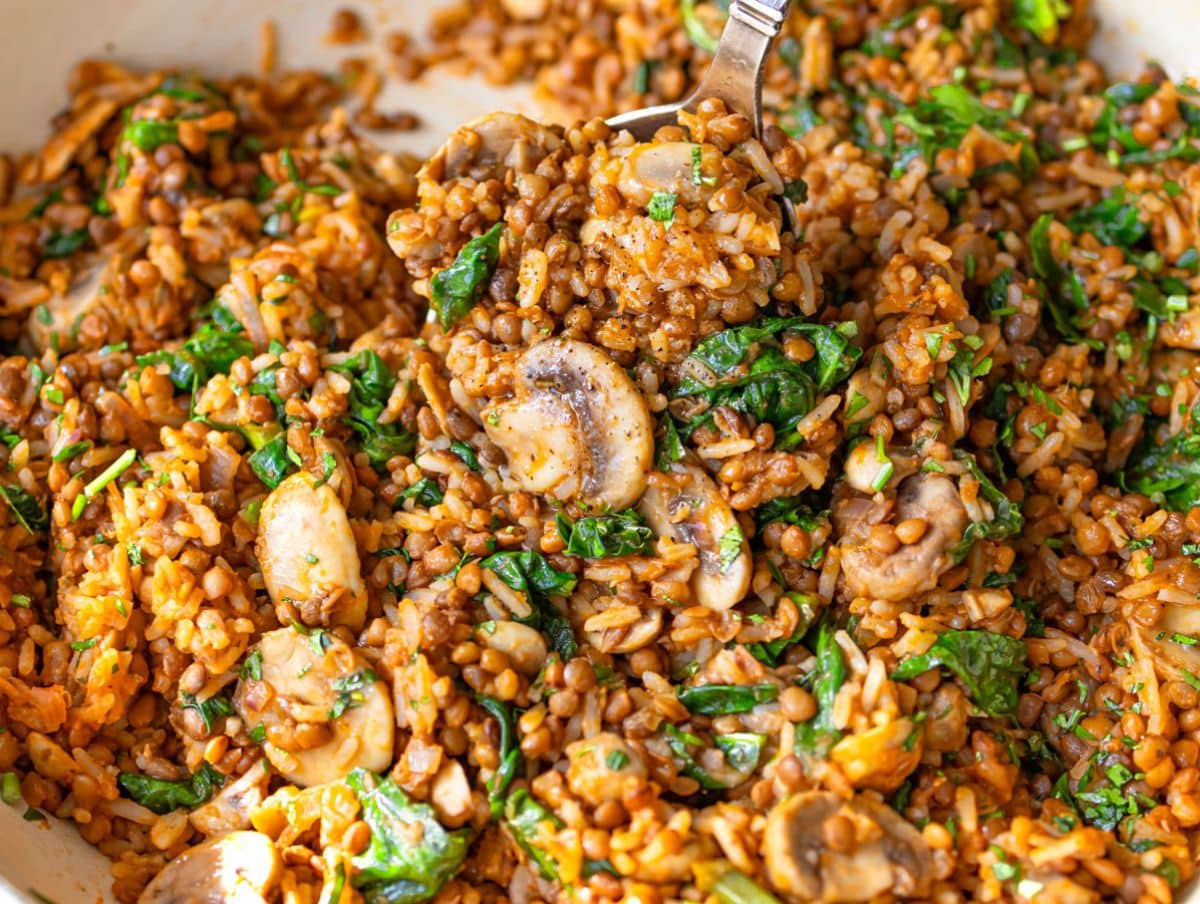 Mediterranean mushroom rice and lentil stir fry garnished in a skillet with fresh herbs.