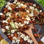 One pan Mediterranean black beans and rice served with feta parsley and lemon on wooden table.