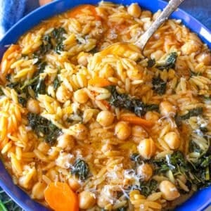 One skillet chickpea orzo recipe with kale carrots and tomato broth in a bowl.