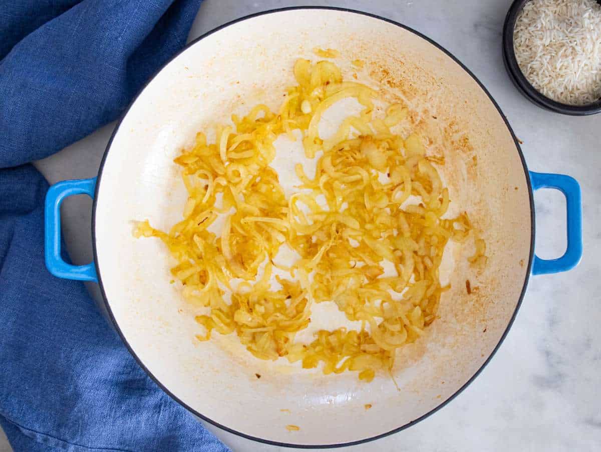 Step 1 – onions cooking in skillet until soft and golden for Mediterranean lentils and rice.