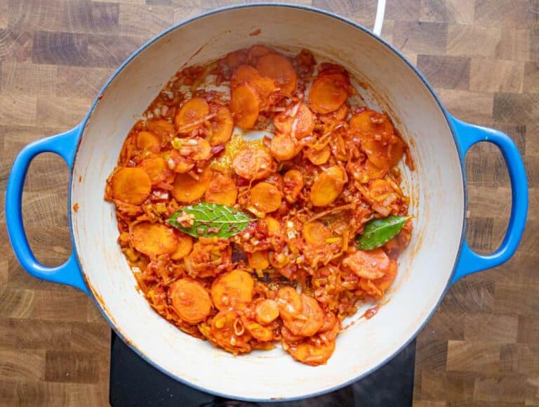 Step 2 Stirring garlic tomato paste and bay leaves in the pot for flavor.