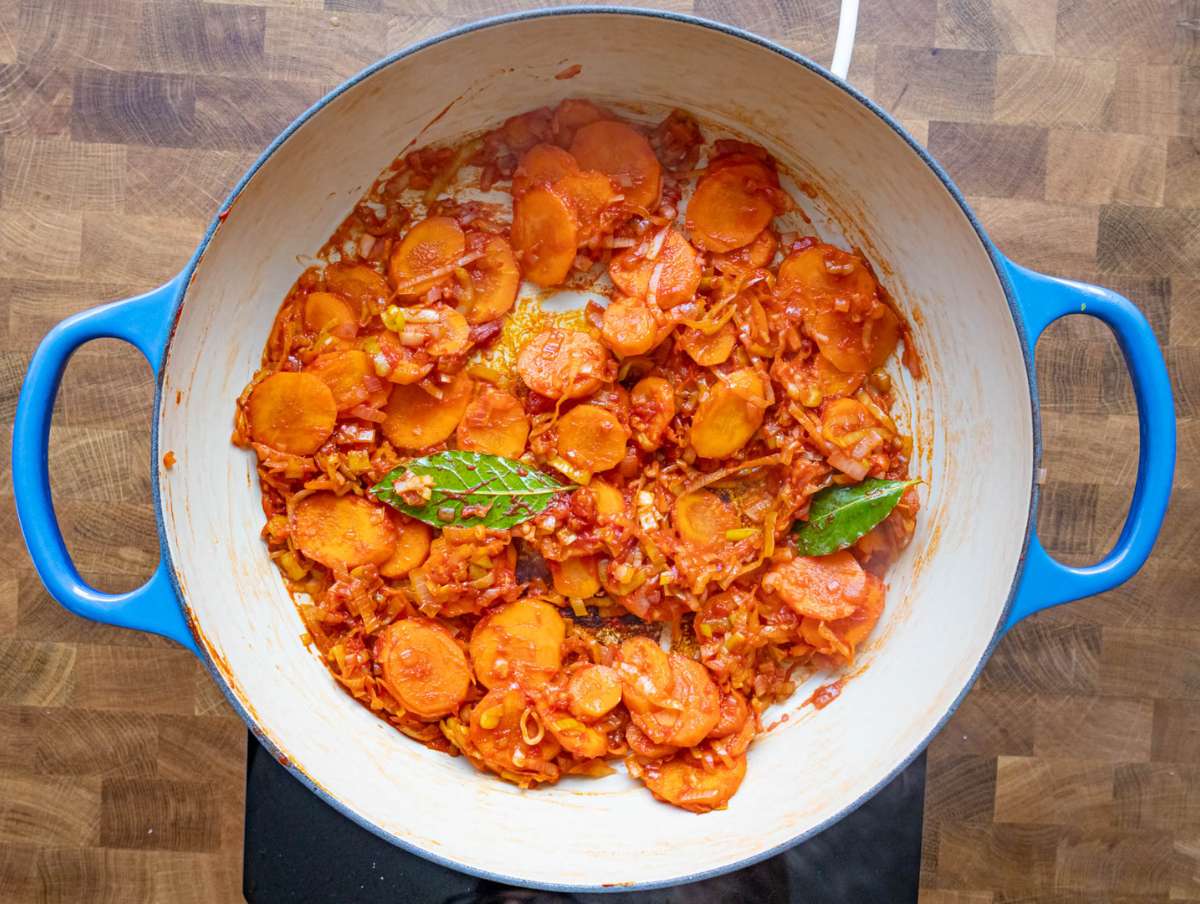 Step 2 Stirring garlic tomato paste and bay leaves in the pot for flavor.