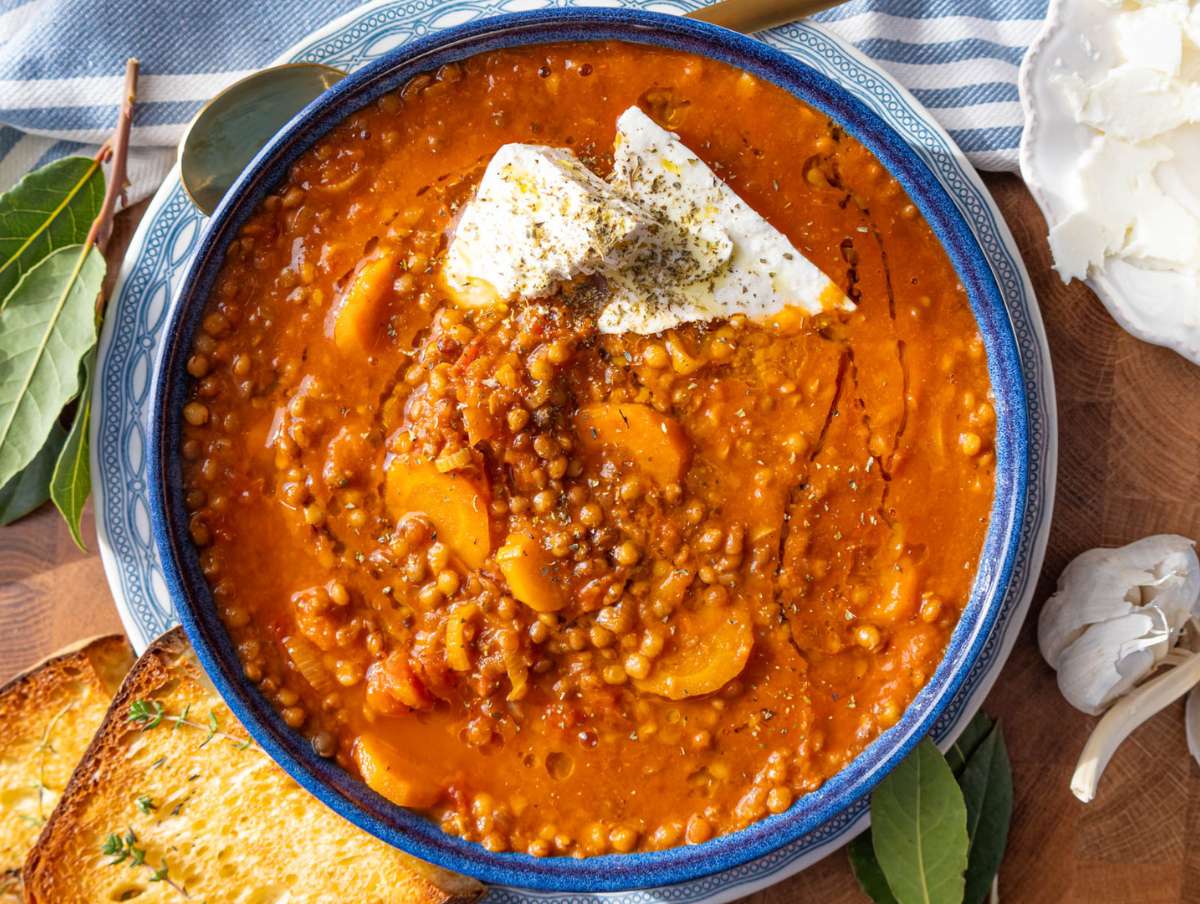 Step 4 Hearty Greek lentil soup in a bowl topped with olive oil oregano and chunks of feta.