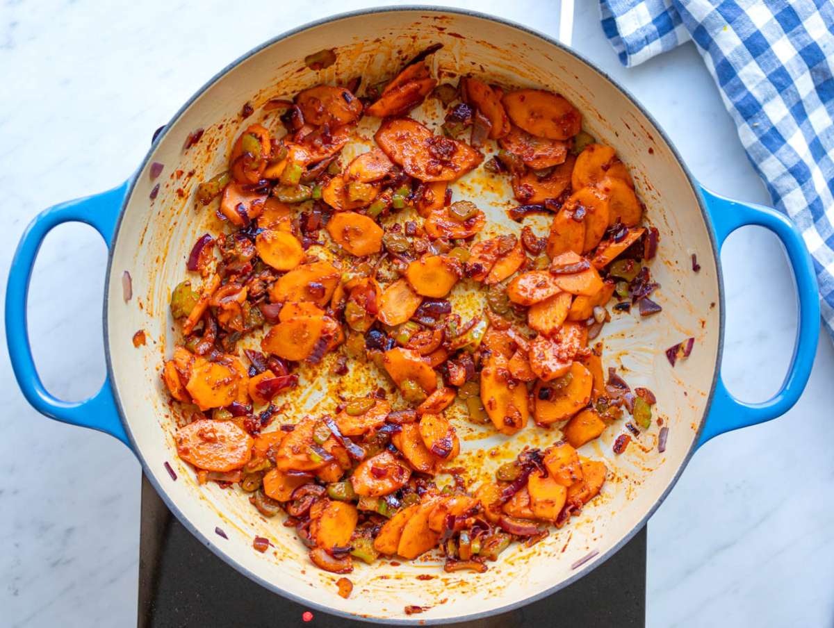 Step one onion carrot and celery cooking with tomato paste and spices to build flavor base.