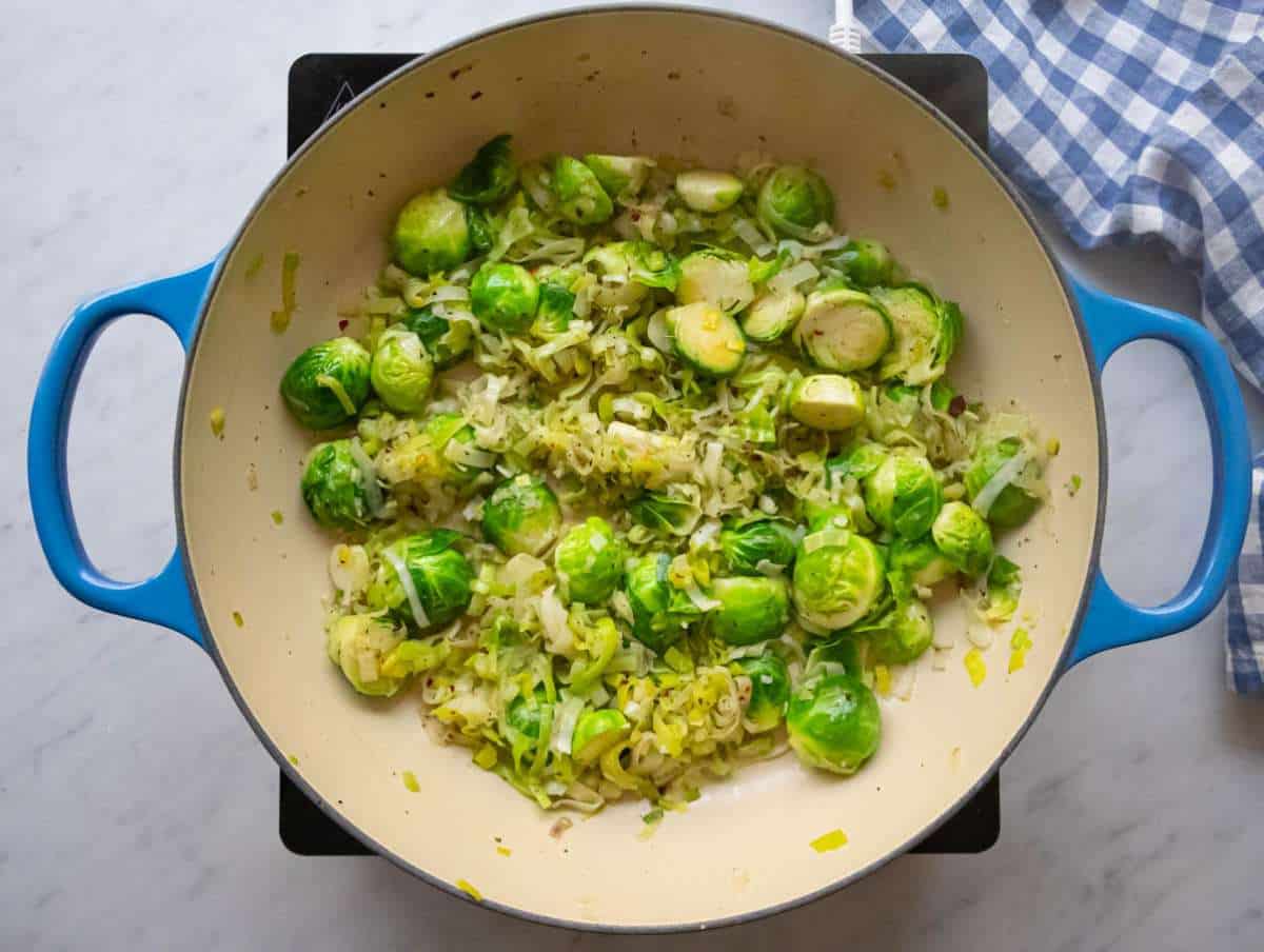 Step one sautéing leeks green onions and Brussels sprouts in olive oil.