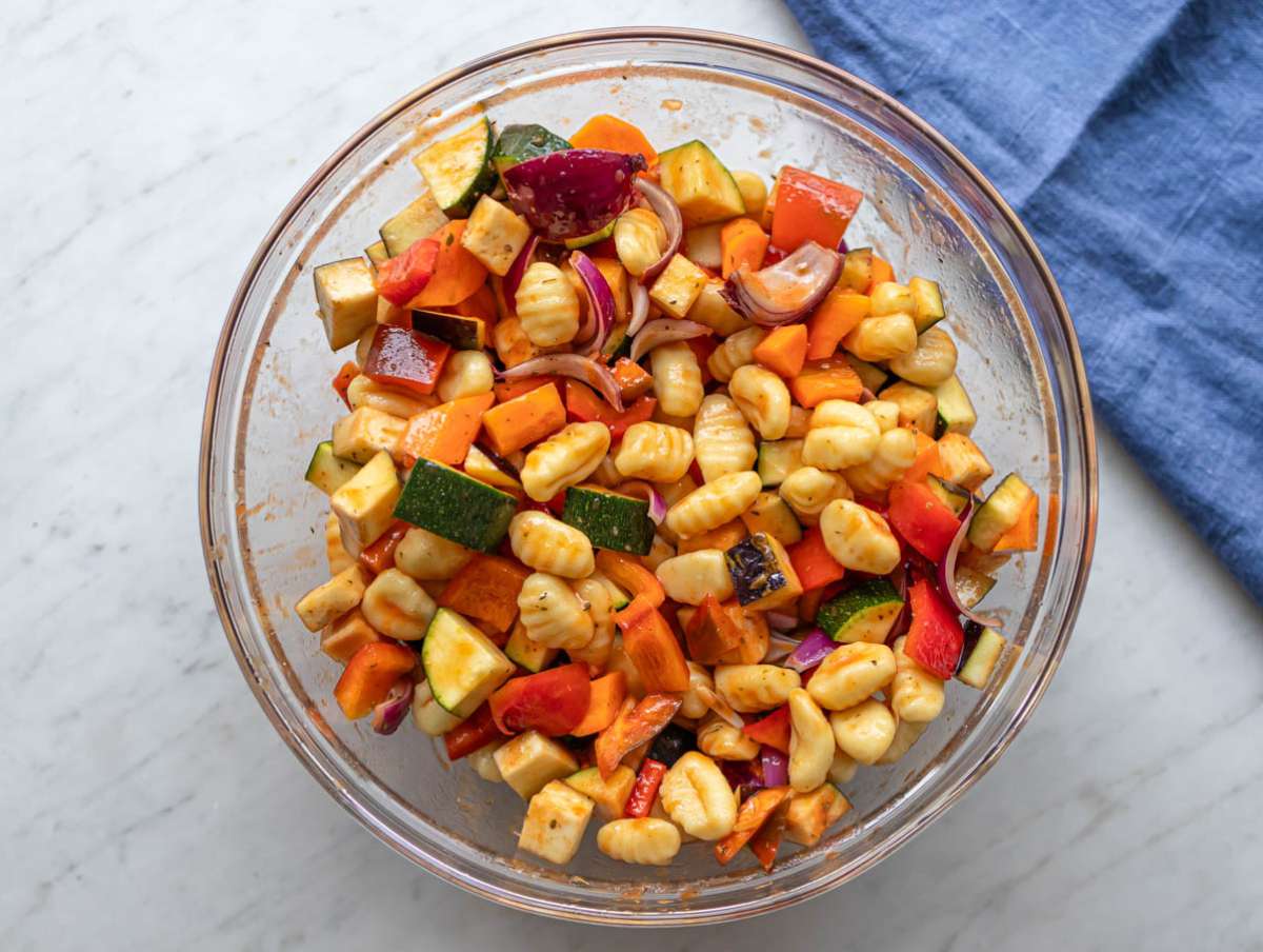 Step two adding chopped vegetables and uncooked gnocchi to bowl for tossing.