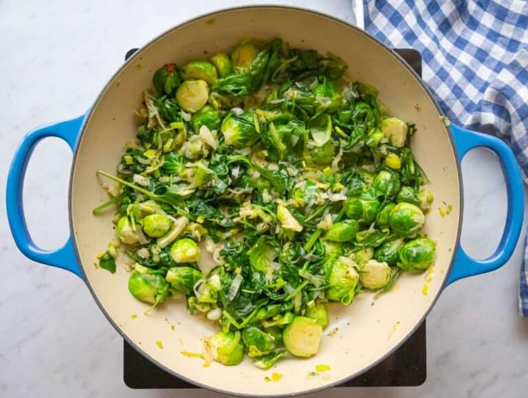 Step two wilting fresh spinach into the vegetable mixture.