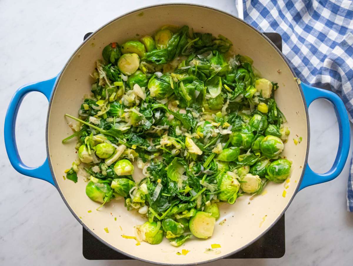 Step two wilting fresh spinach into the vegetable mixture.
