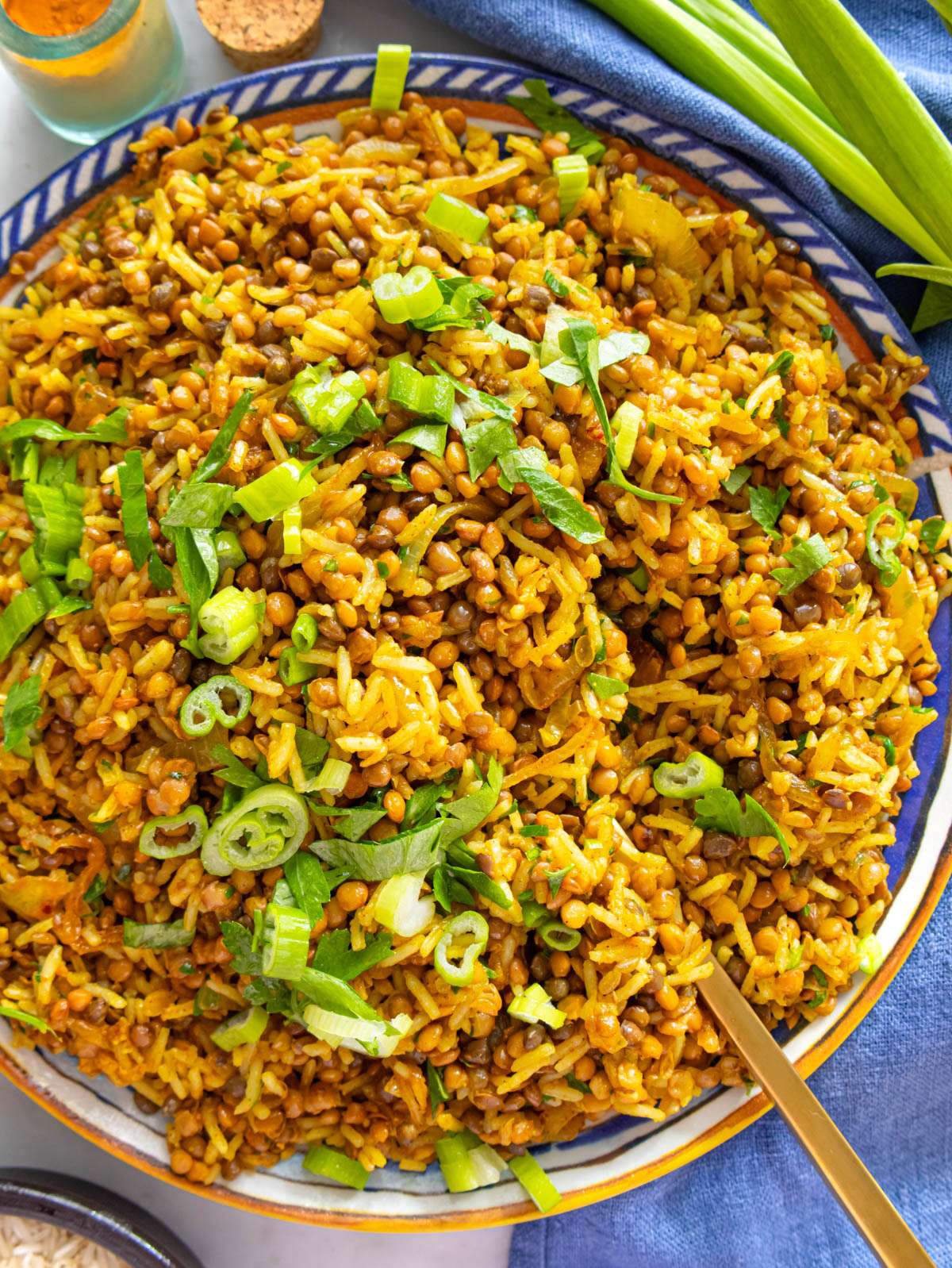 Top-down finished dish – one pot Mediterranean lentils and rice served with lemon wedges.