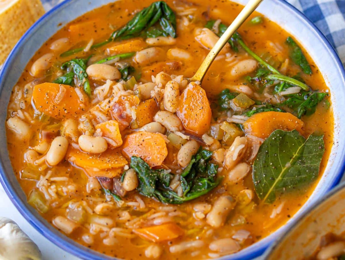 Vibrant Greek bean stew with beans rice carrots and spinach in a cozy bowl.