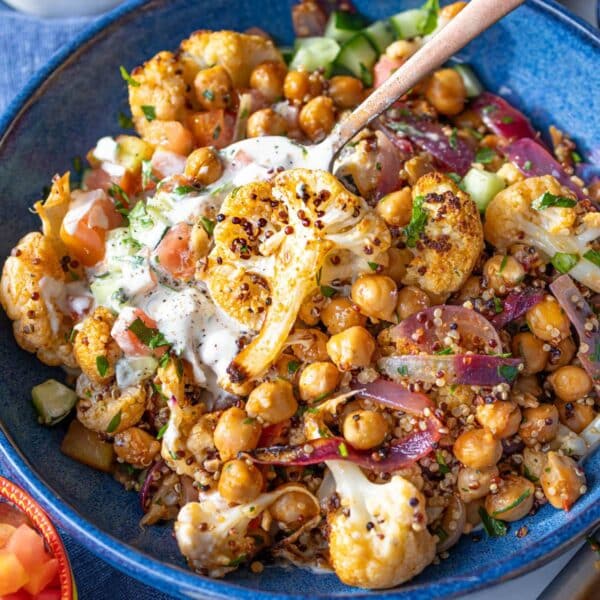 Cauliflower shawarma bowl with roasted vegetables quinoa and fresh toppings in a vibrant bowl.