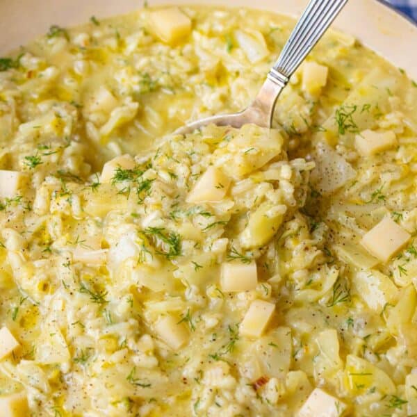Creamy cabbage rice with melting cheese being served from a large dutch oven.