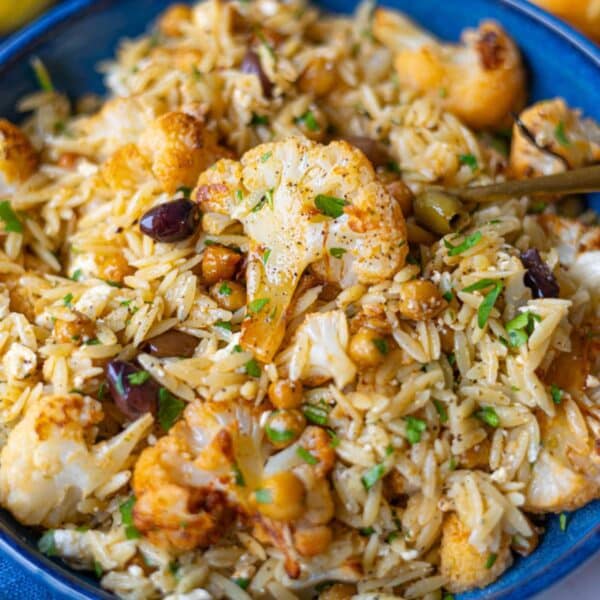 Feature image showing vibrant roasted cauliflower orzo with olives feta and parsley.