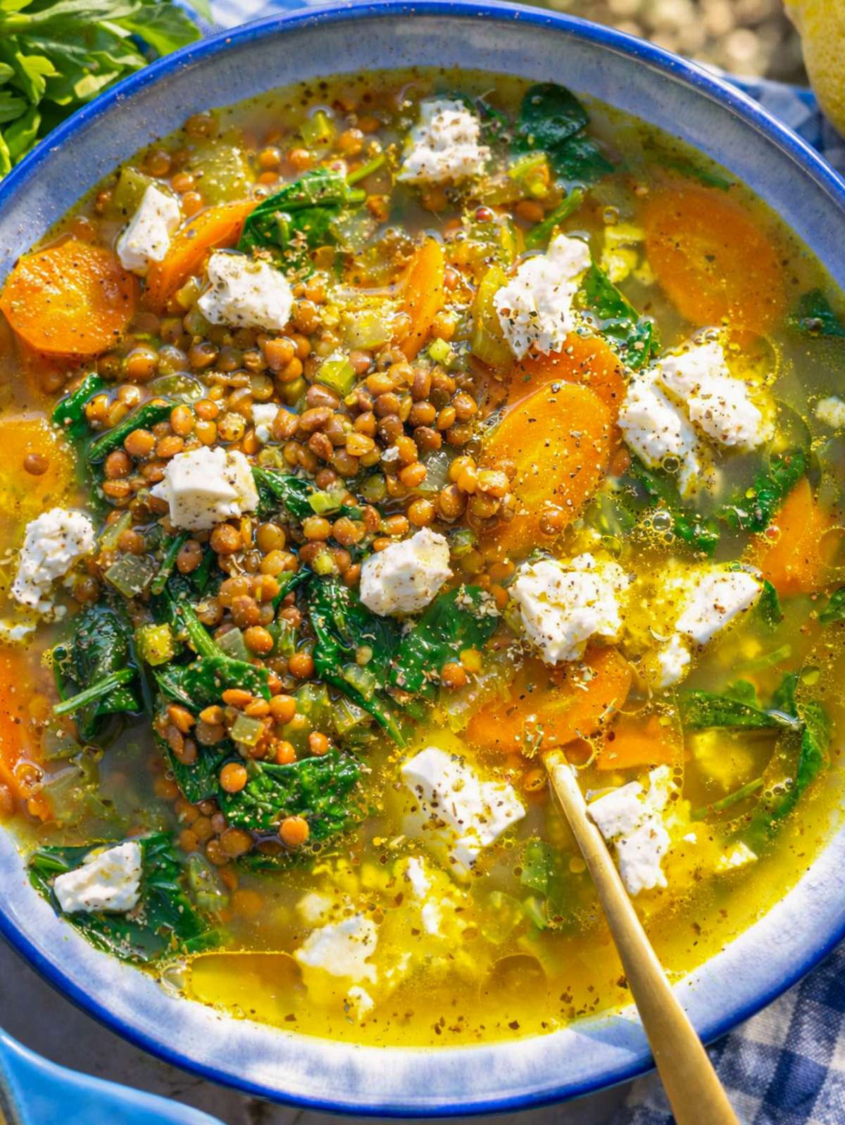 Finished lemon lentil soup served in bowl with feta and lemon slices.