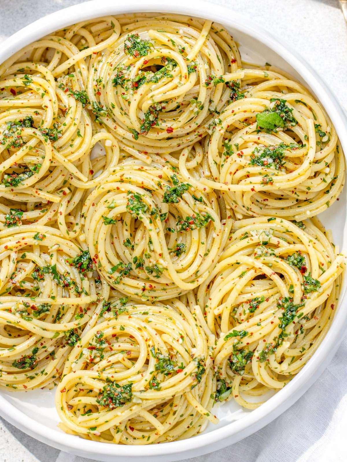 Finished spaghetti aglio e olio plated and glossy with olive oil and parsley.