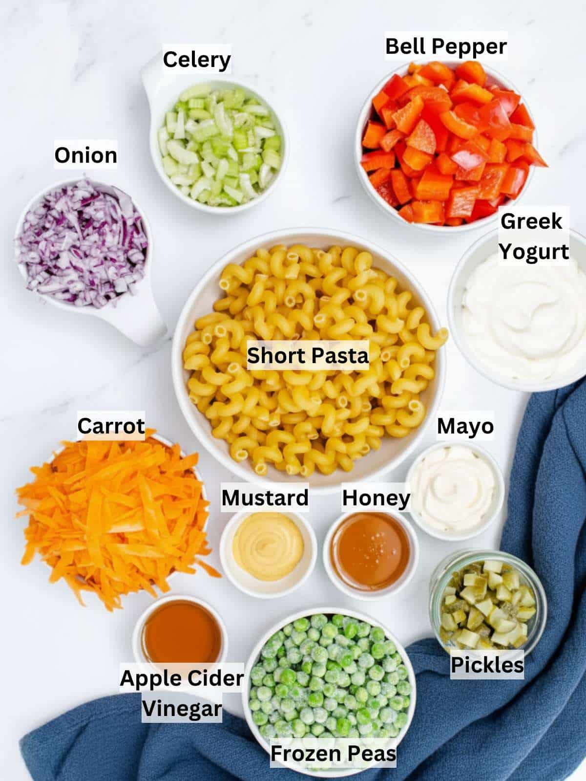Ingredients for Greek yogurt macaroni salad pasta peas vegetables yogurt dressing on countertop.