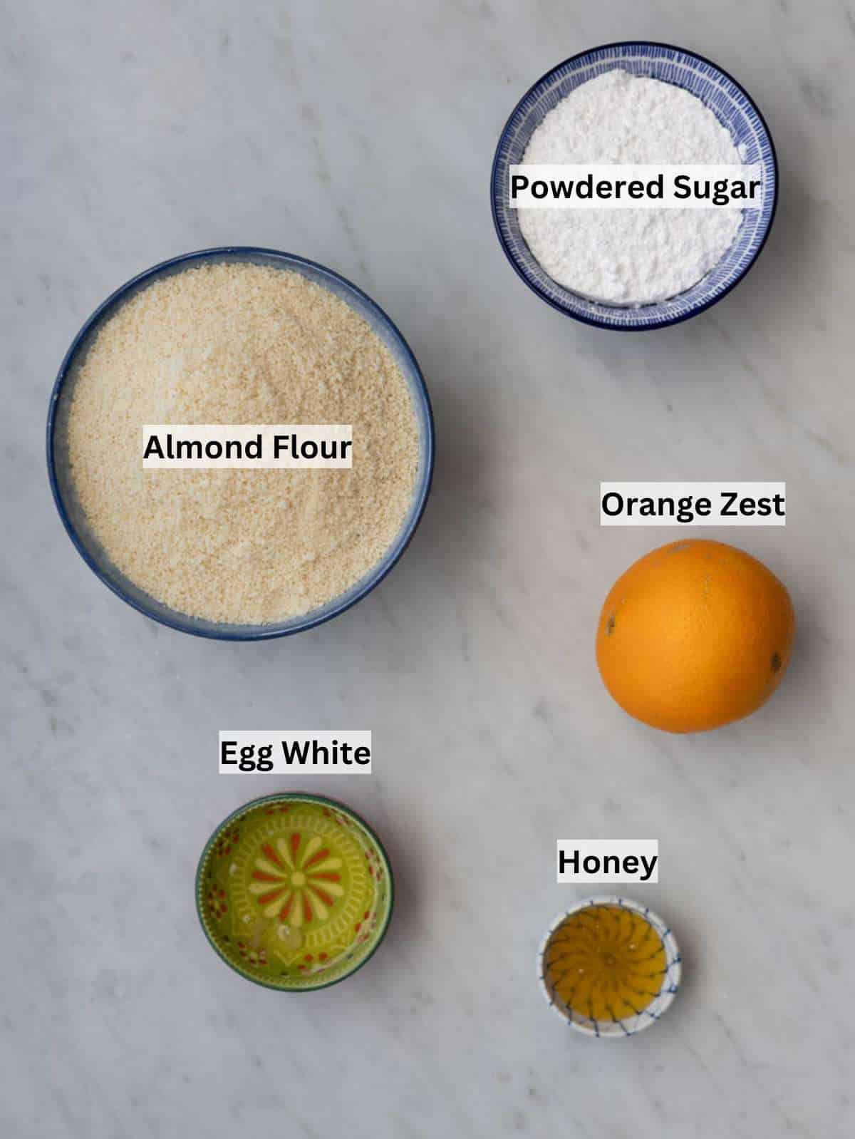 Ingredients for Italian almond cookies including almond flour powdered sugar egg white honey and orange.