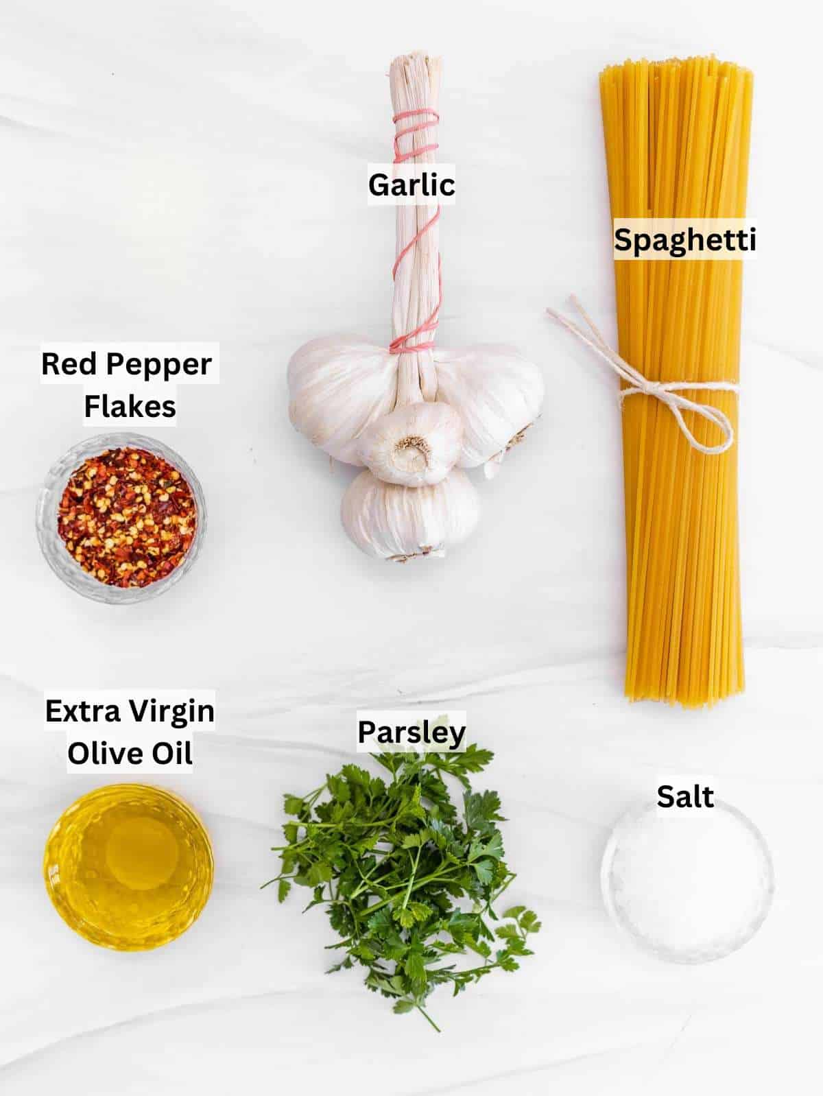 Ingredients for spaghetti aglio e olio garlic olive oil chili parsley and dry pasta.