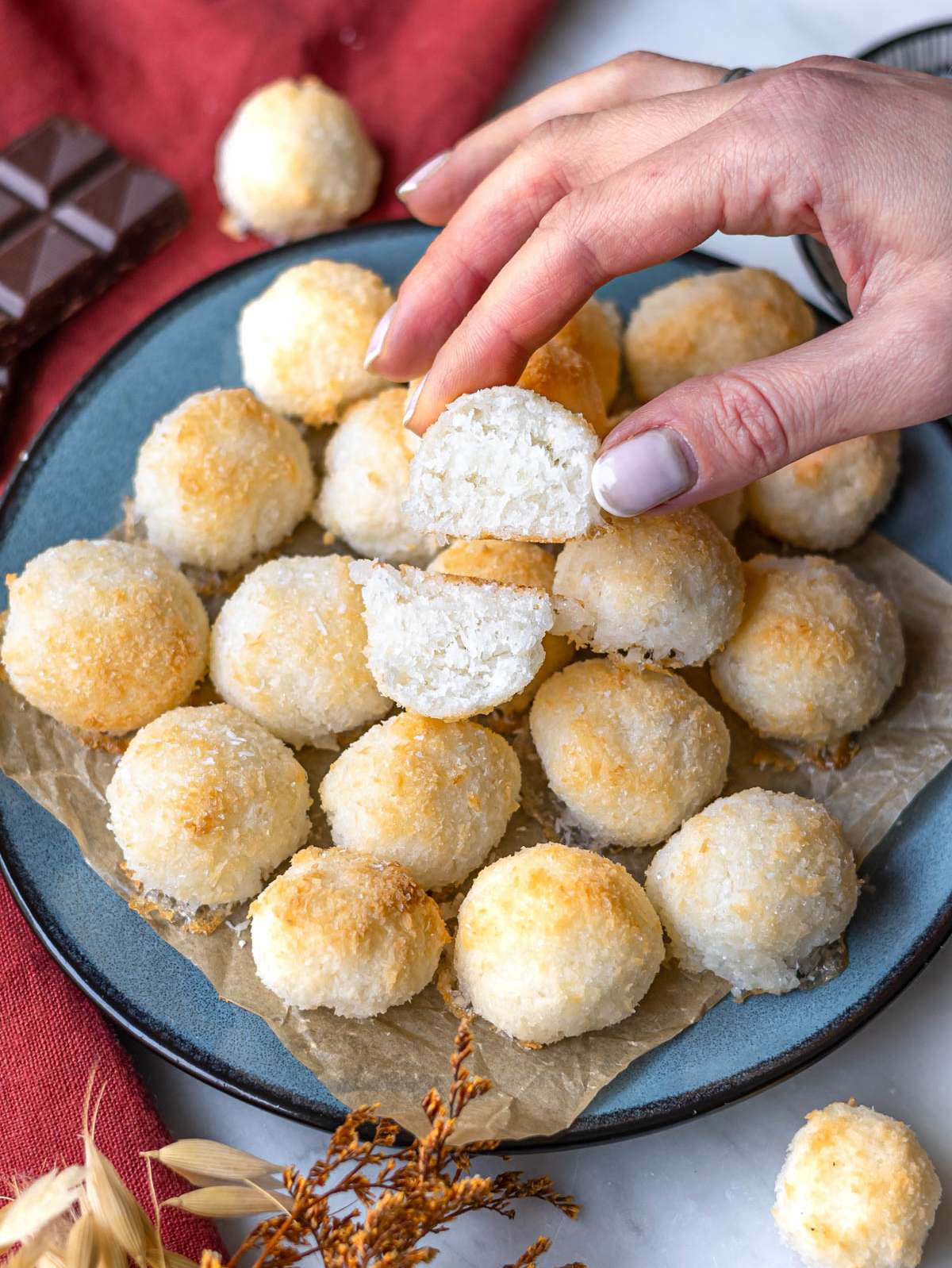 Louiseโs hand holding cut open coconut macaroon showing tender moist inside.