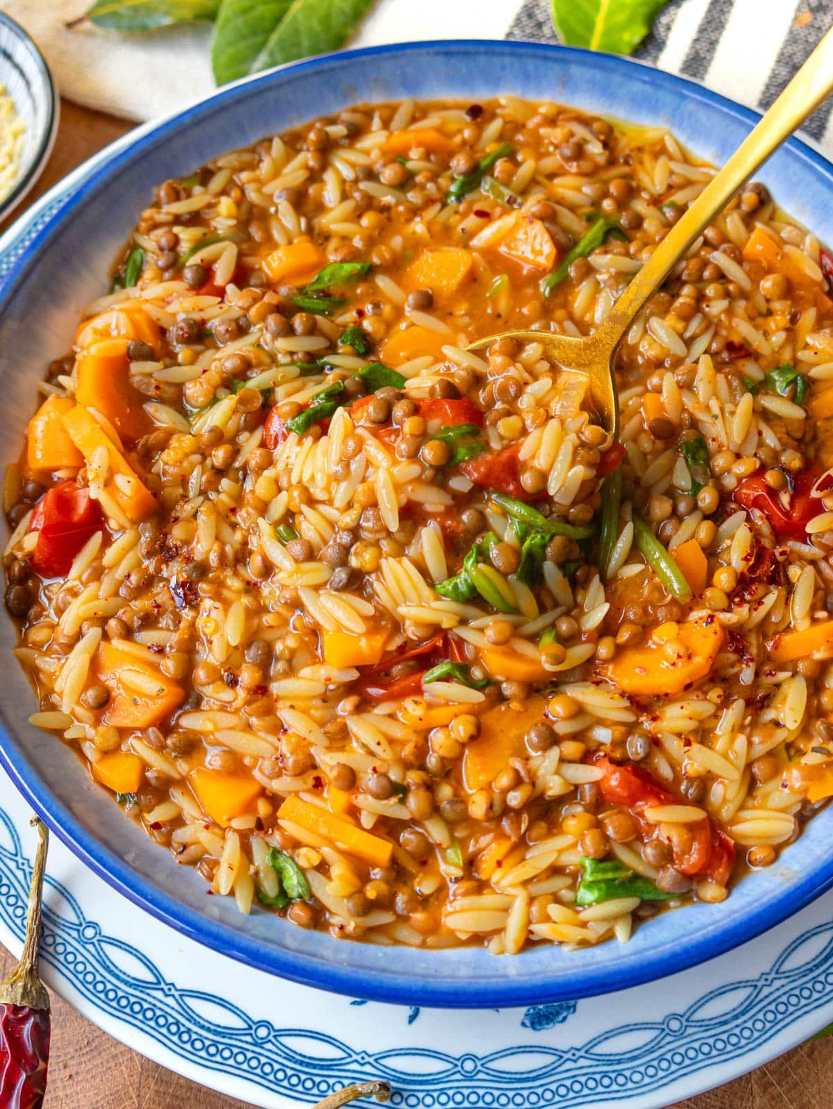 Mediterranean orzo recipe with tomatoes, carrots, spinach, and herbs in a bowl.