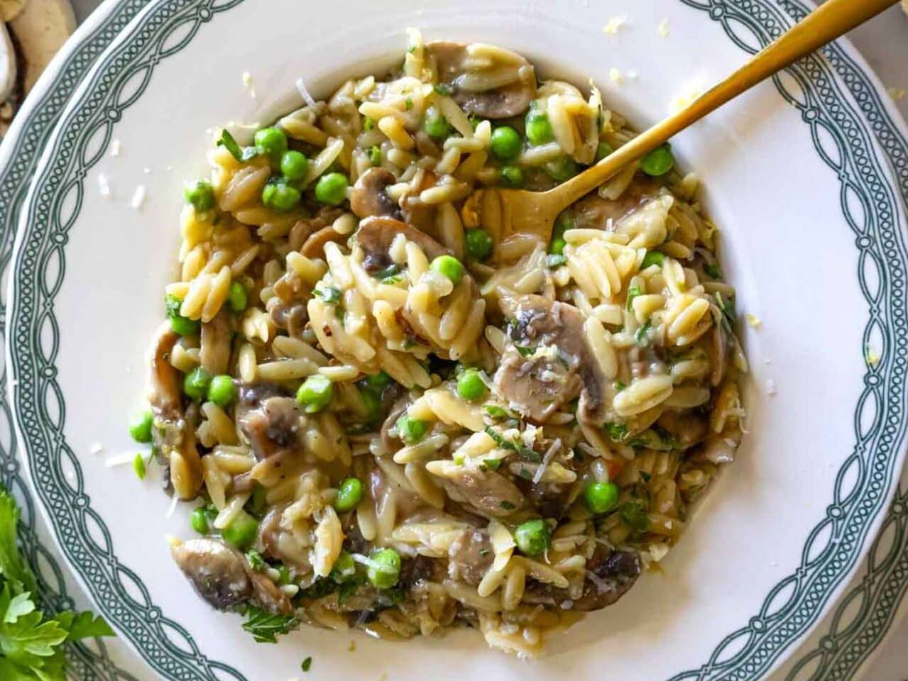 Mushroom orzo recipe served in green and white plate with lemon zest.