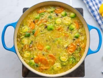 Step 2 Adding orzo beans and broth to skillet for one pot vegetable orzo.