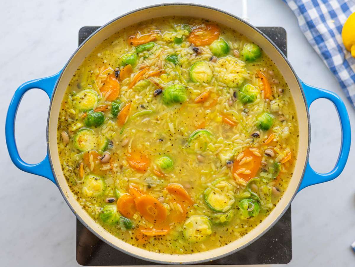 Step 2 Adding orzo beans and broth to skillet for one pot vegetable orzo.