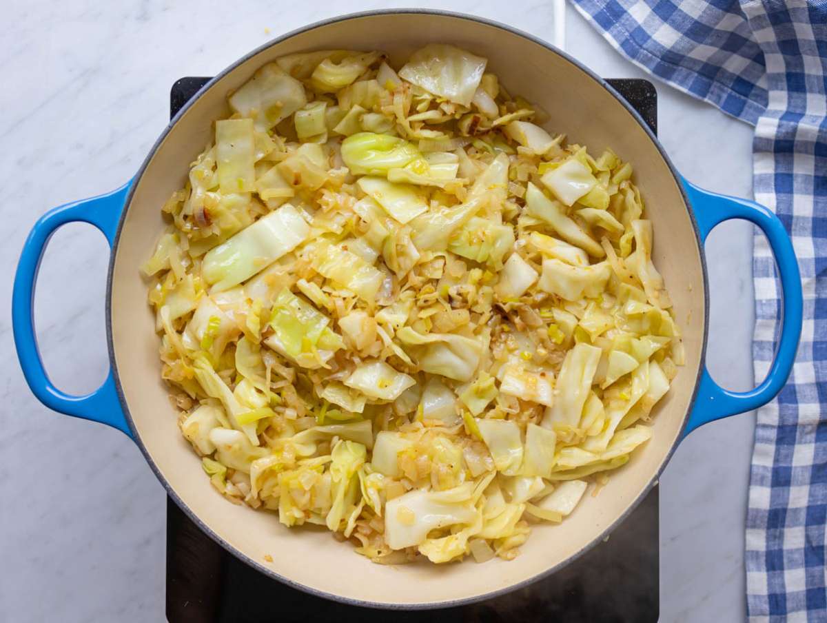 Step 2 Braised cabbage strips cooking down in a large pot with onions and garlic.