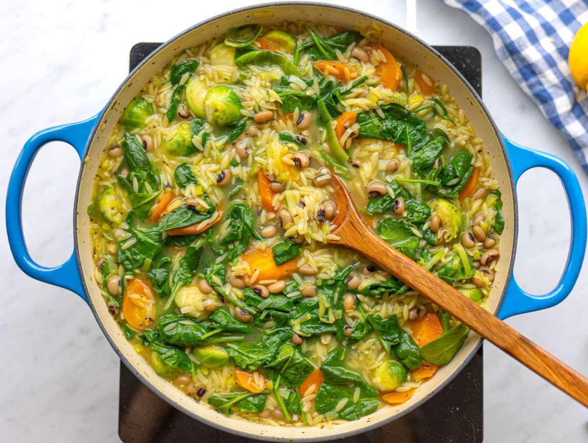 Step 3 Stirring spinach into creamy vegetable orzo near the end of cooking.