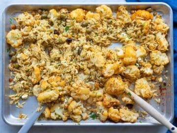 Step 3 Tossing hot orzo with roasted vegetables olives feta and parsley on sheet pan.
