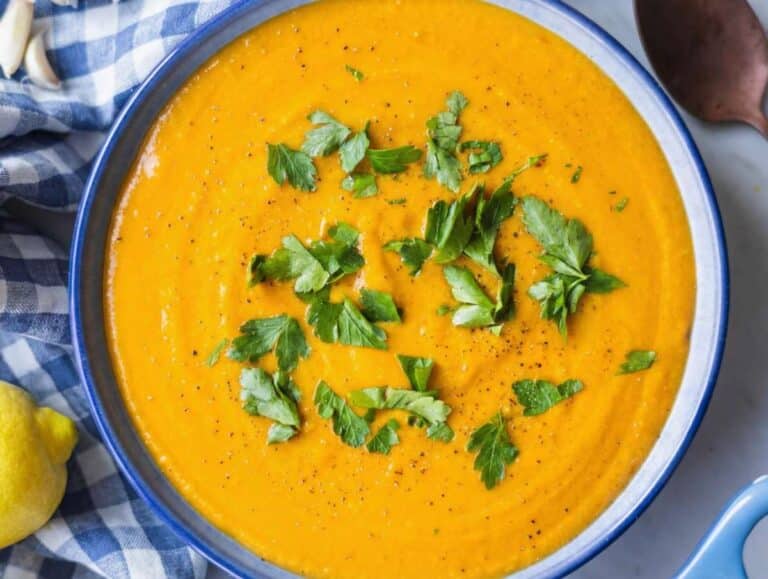 Step 4 Creamy sweet potato chickpea soup served in a blue bowl with parsley and black pepper.