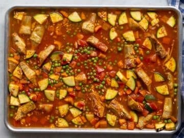 Step two Warm broth poured over seasoned rice and vegetables on sheet pan.