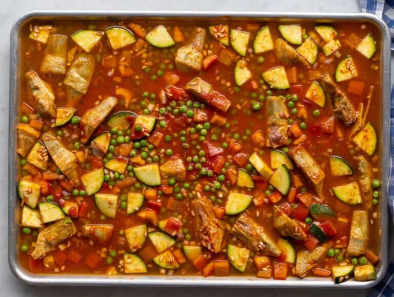 Step two Warm broth poured over seasoned rice and vegetables on sheet pan.