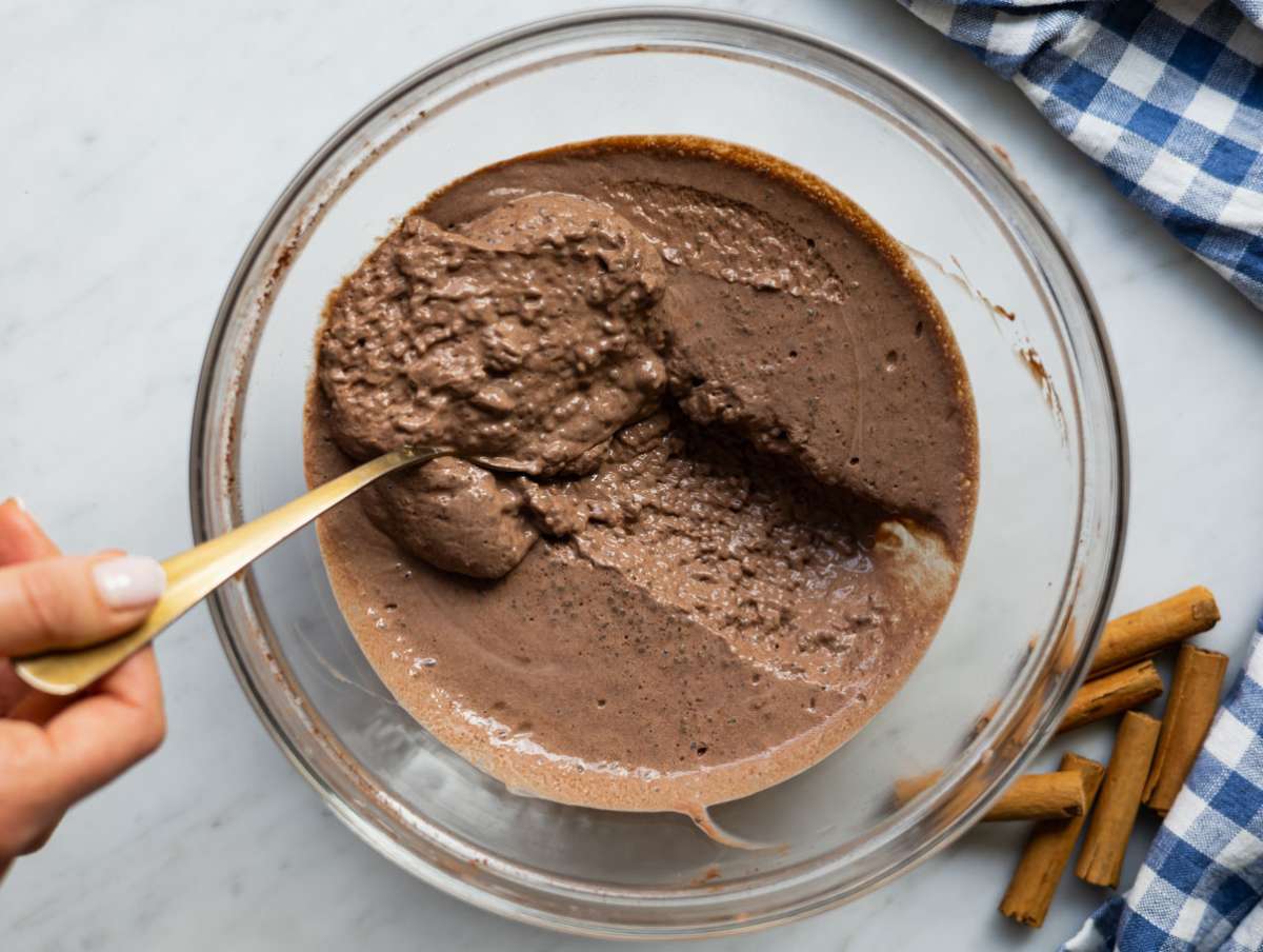 Stirring chocolate chia pudding before serving with fresh fruit and nuts.