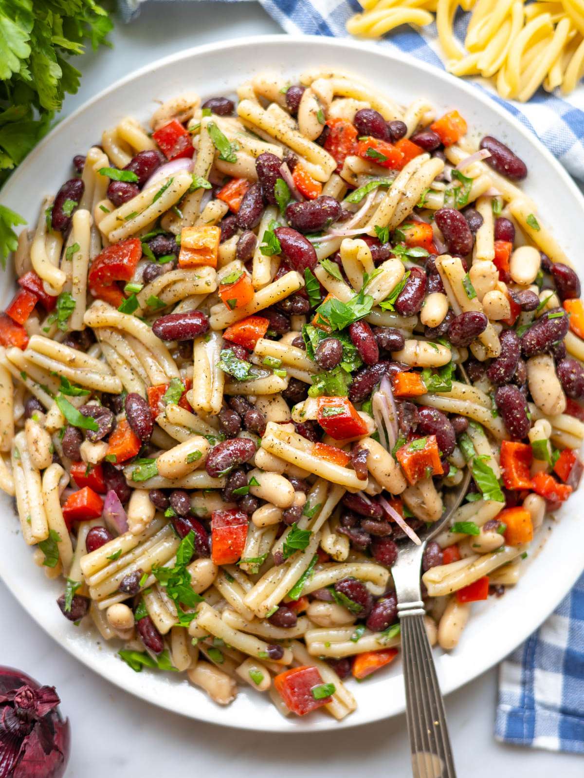 Top down view of 3 bean pasta salad on platter with colorful vegetables.