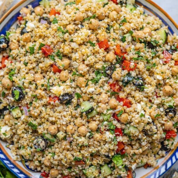 A vibrant Mediterranean bulgur salad with chickpeas, fresh herbs, and diced vegetables served in a bowl on a marble table.