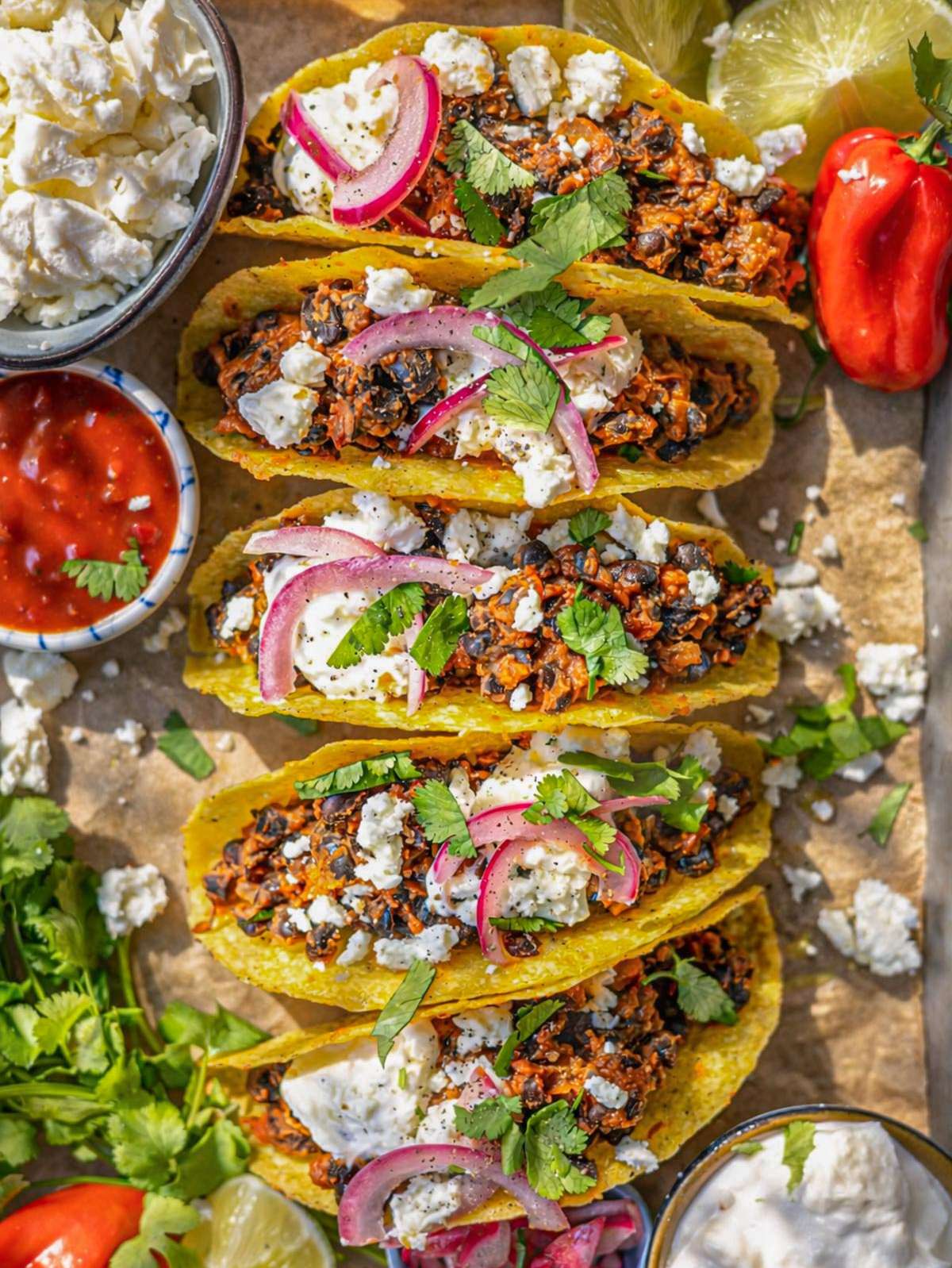 Black bean tacos filled with creamy beans topped with feta yogurt and fresh vegetables.