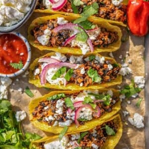 Black bean tacos served simply on a tray with fresh toppings and crunchy taco shells.