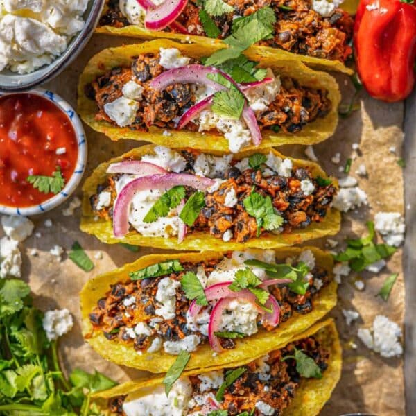 Black bean tacos served simply on a tray with fresh toppings and crunchy taco shells.