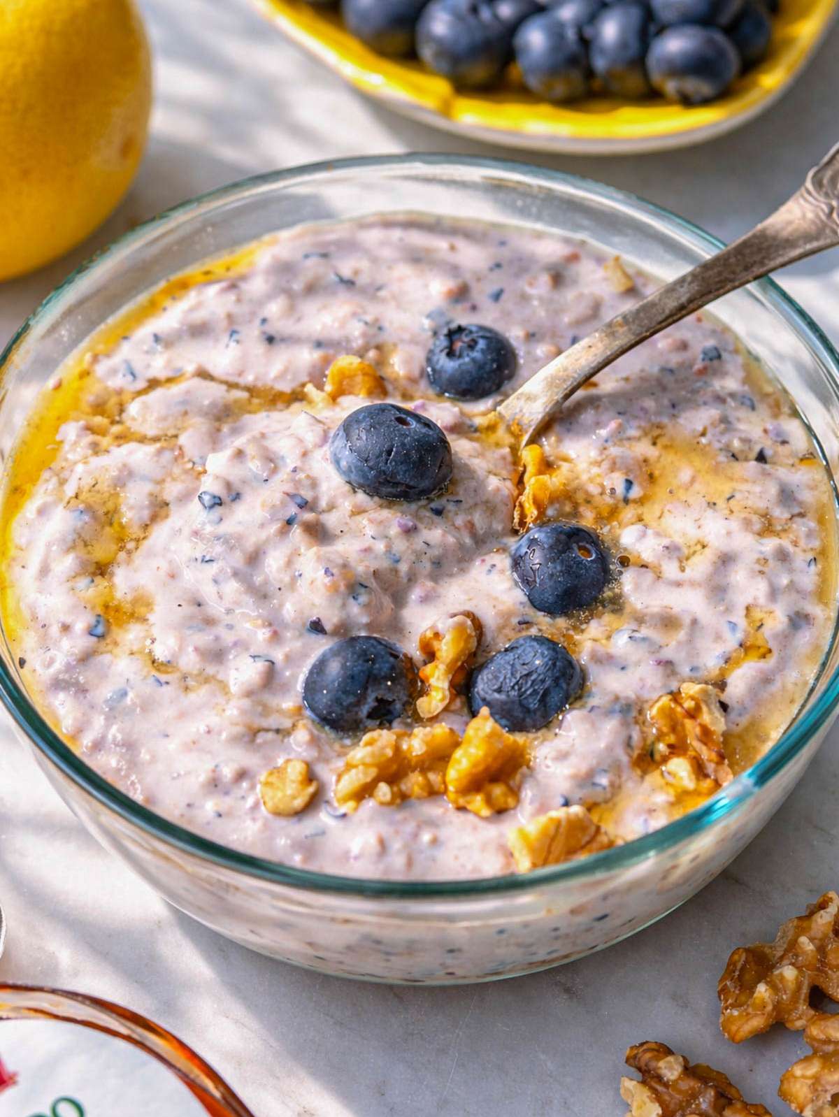 Bowl of creamy blueberry overnight oats topped with whole blueberries and a drizzle of maple syrup.
