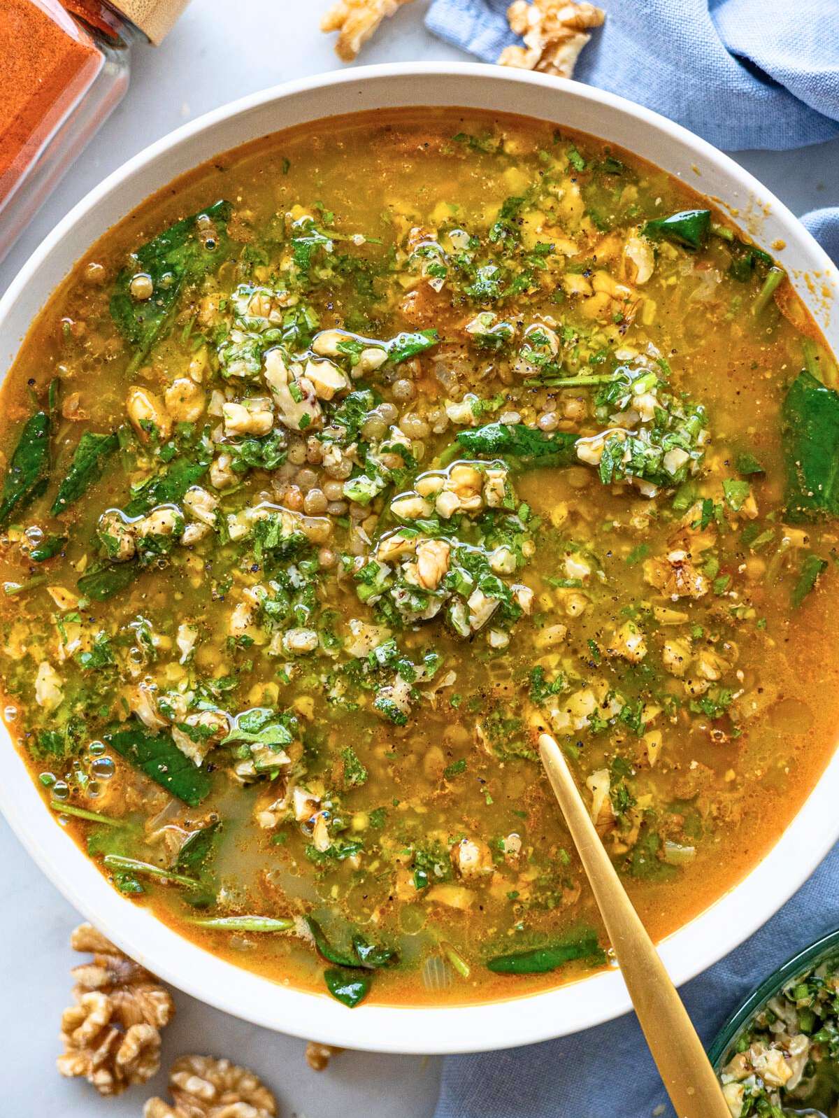 Bowl of lentil soup topped with walnut lemon gremolata and olive oil.