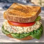 Chickpea Salad Sandwich with Greek Yogurt served on a marble cutting board with fresh vegetables.