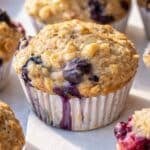 Close up of a healthy blueberry muffin showing golden top with oats and blueberries.