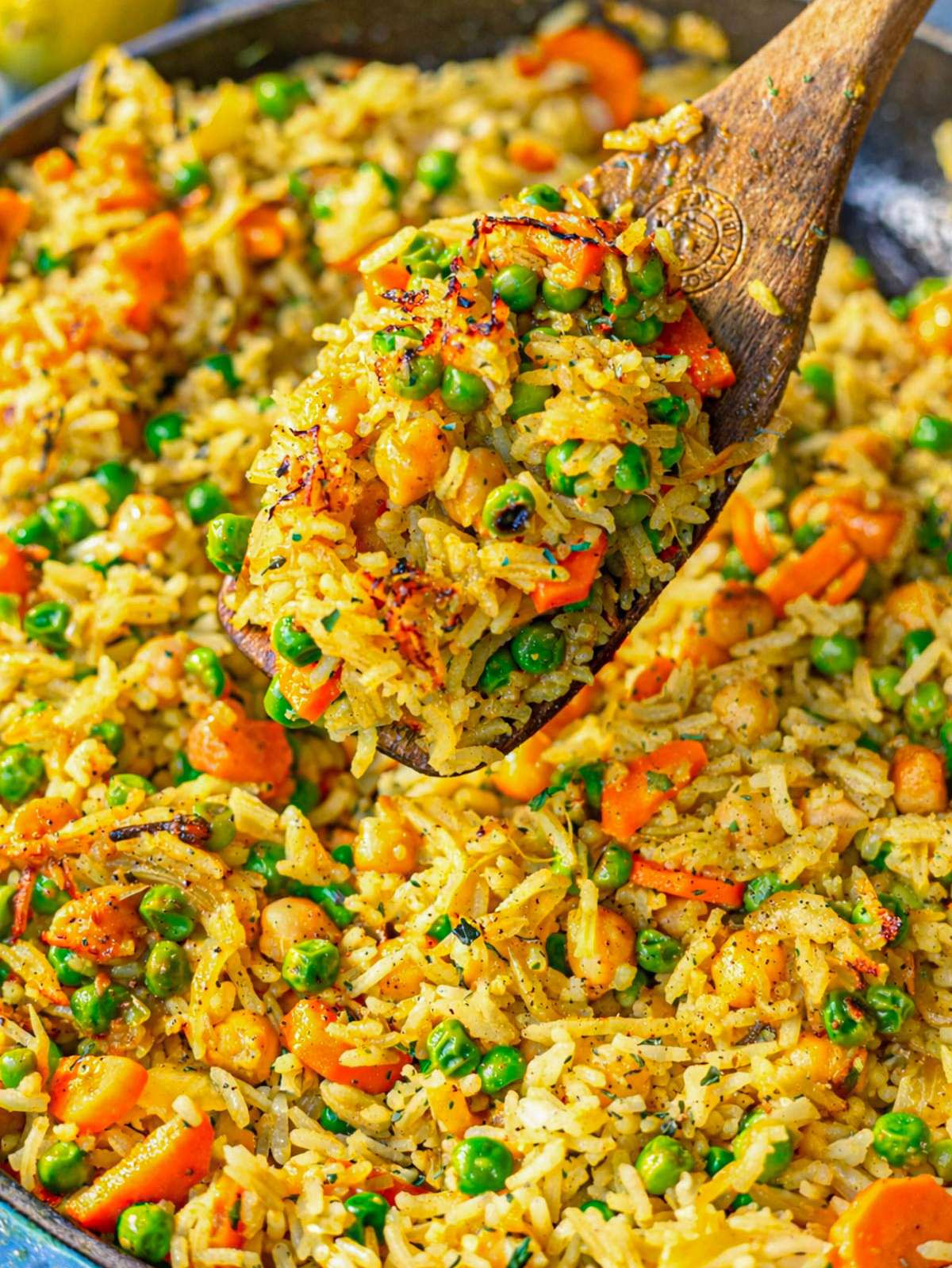 Close-up of fluffy rice coated in spices with chickpeas, peas, and carrots.