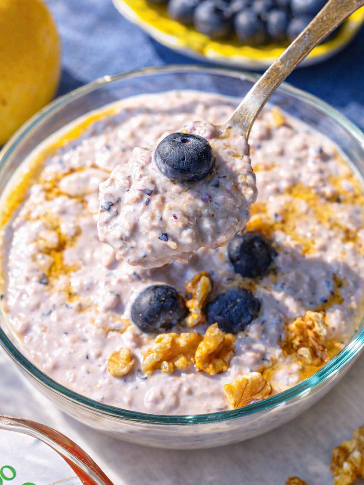 Close-up of spoon scooping thick, purple blueberry overnight oats showing creamy texture.